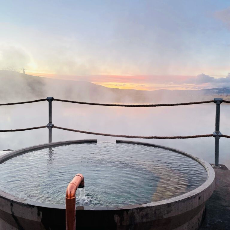 A hot springs sulfur water soaking tub at the Hot Lake hotel in LaGrande Oregon, overlooking the Hot Lake at sunset, mountain range covered by the steam from the lake.