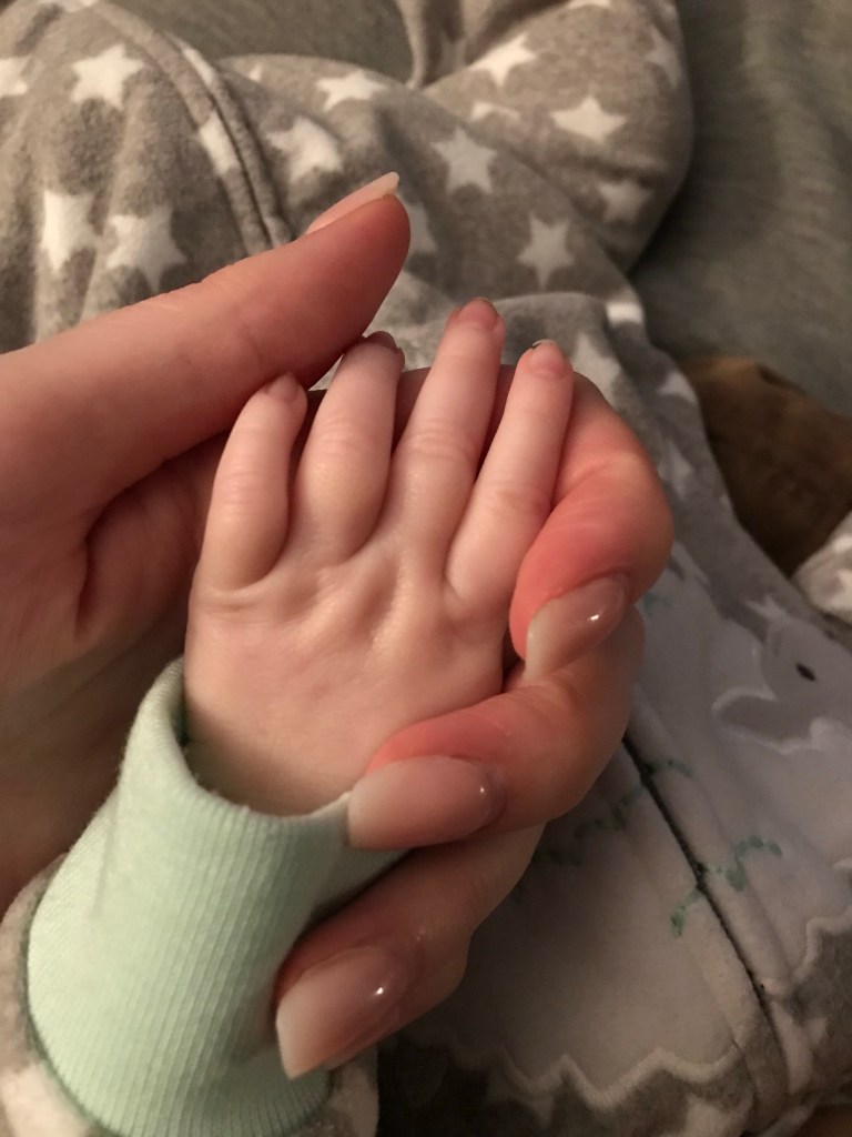 Mother and new born daughter holding hands