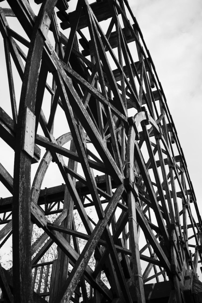 Large wooden roller coaster section in black and white