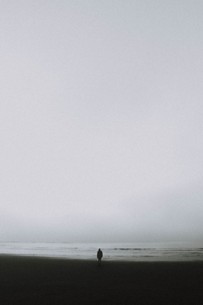 Foggy beach scene with someone walking alone in the distance